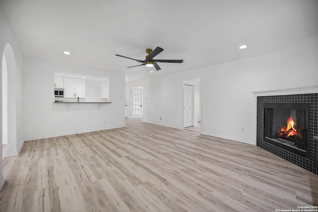 unfurnished living room featuring a fireplace, light hardwood / wood-style floors, and ceiling fan