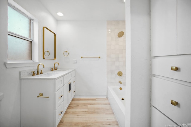 bathroom with tiled shower / bath, vanity, and hardwood / wood-style flooring