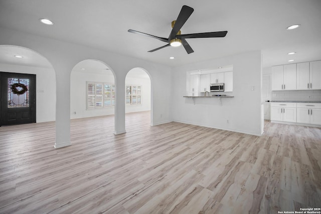 unfurnished living room featuring ceiling fan, sink, and light hardwood / wood-style flooring