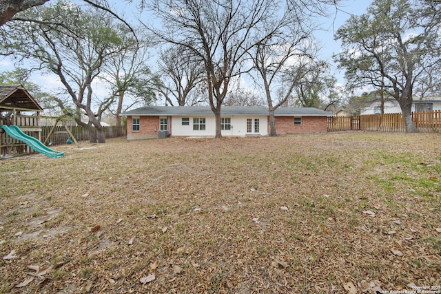 rear view of property featuring a lawn and a playground