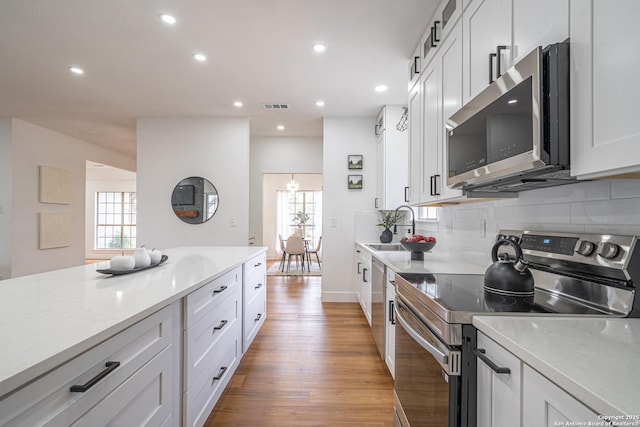 kitchen featuring white cabinets, stainless steel appliances, a healthy amount of sunlight, and sink