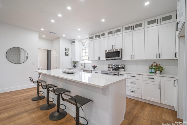 kitchen featuring a kitchen bar, white cabinetry, a kitchen island, and appliances with stainless steel finishes