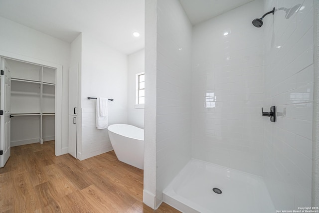 bathroom with hardwood / wood-style flooring and shower with separate bathtub