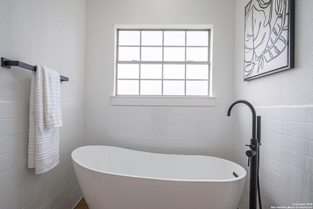 bathroom featuring a bathtub and tile walls