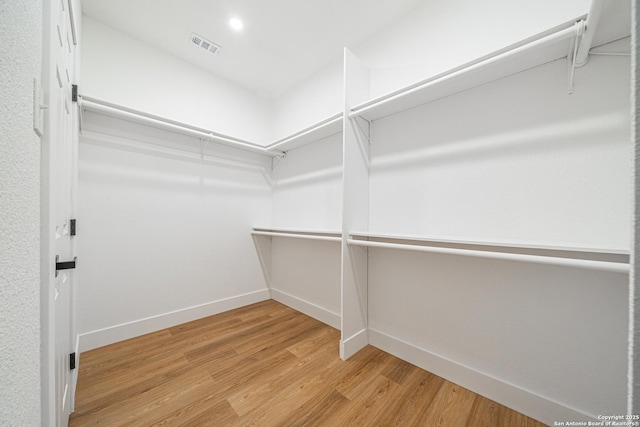 walk in closet with light hardwood / wood-style flooring