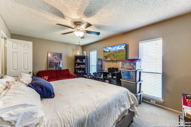 bedroom with carpet, ceiling fan, a textured ceiling, and multiple windows