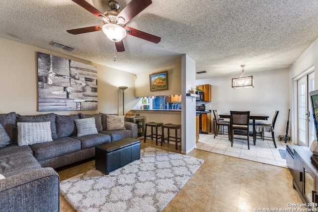 tiled living room featuring a textured ceiling and ceiling fan