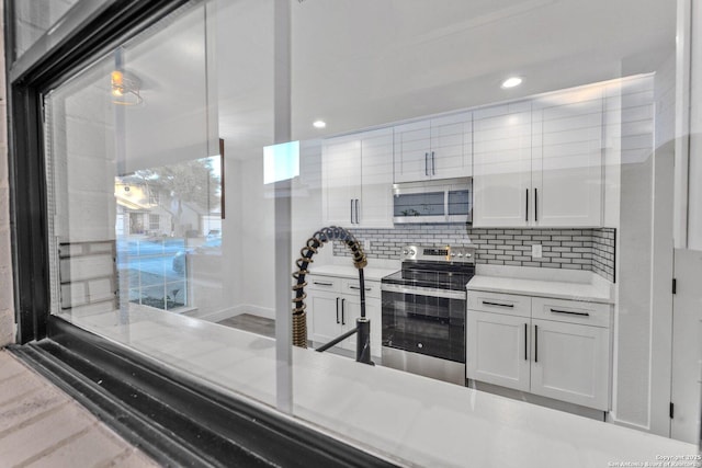 kitchen featuring decorative backsplash, white cabinetry, and stainless steel electric range oven