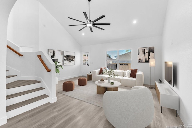 living room featuring ceiling fan, high vaulted ceiling, and light hardwood / wood-style flooring