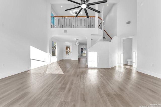 unfurnished living room with ceiling fan, hardwood / wood-style floors, and high vaulted ceiling