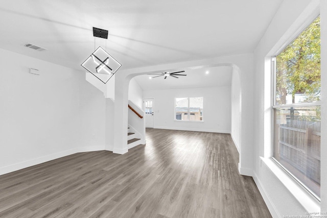 unfurnished living room featuring ceiling fan, dark wood-type flooring, and a wealth of natural light