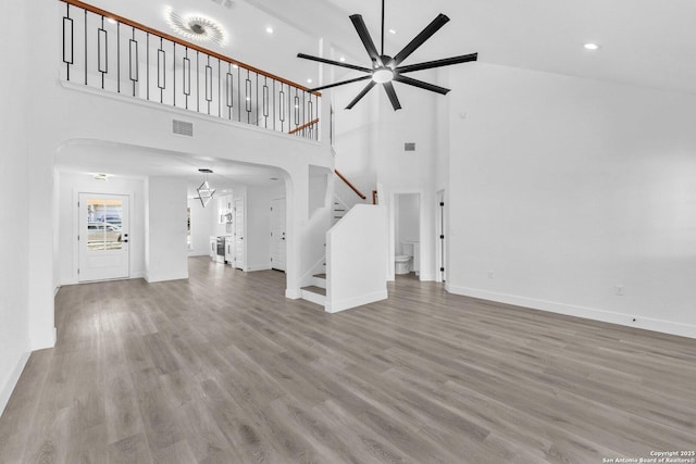 unfurnished living room with ceiling fan, high vaulted ceiling, and wood-type flooring