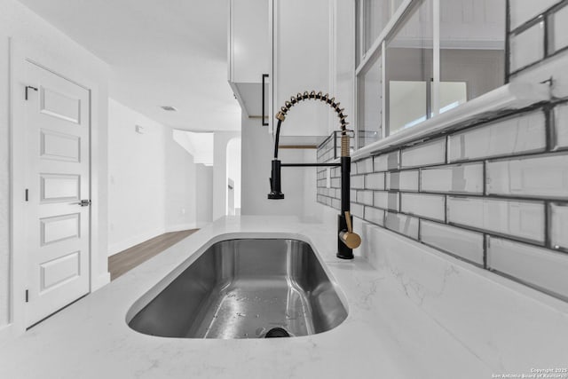 room details featuring light stone countertops, white cabinetry, and sink