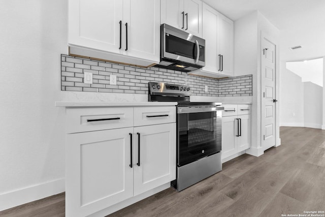 kitchen featuring decorative backsplash, white cabinetry, light wood-type flooring, and appliances with stainless steel finishes