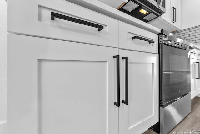 interior details with white cabinets and light hardwood / wood-style floors