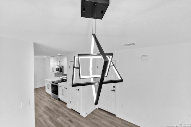 room details featuring backsplash, white cabinetry, light hardwood / wood-style floors, and appliances with stainless steel finishes