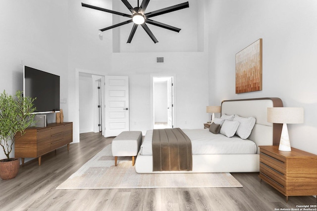 bedroom featuring hardwood / wood-style flooring, ceiling fan, and a high ceiling