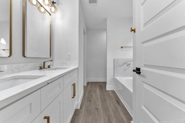 bathroom with hardwood / wood-style flooring, vanity, and a bath