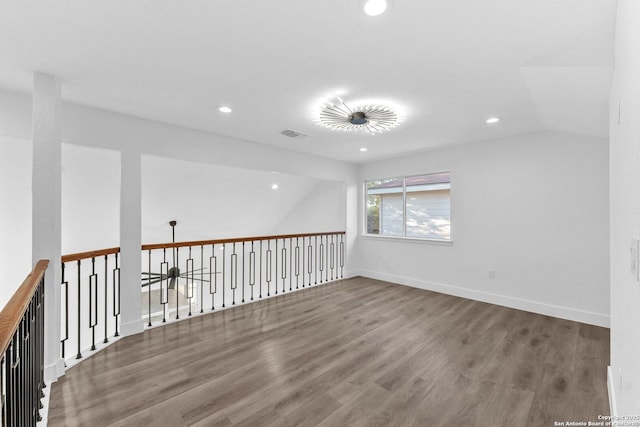 empty room with vaulted ceiling and hardwood / wood-style flooring