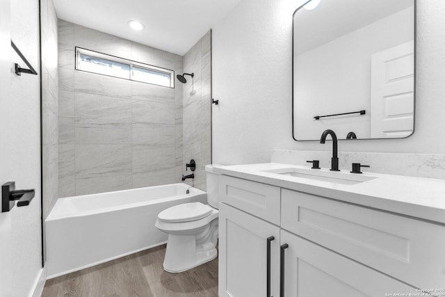 full bathroom with vanity, wood-type flooring, tiled shower / bath combo, and toilet