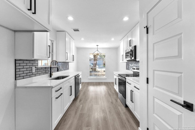 kitchen with white cabinets, pendant lighting, sink, and appliances with stainless steel finishes