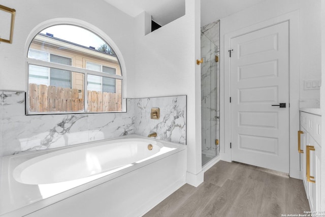 bathroom featuring independent shower and bath, plenty of natural light, and wood-type flooring