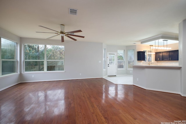 unfurnished living room with ceiling fan, sink, and dark wood-type flooring