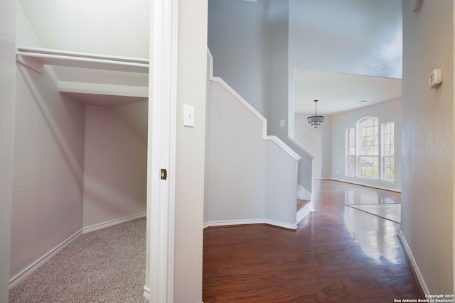 stairs featuring wood-type flooring and an inviting chandelier