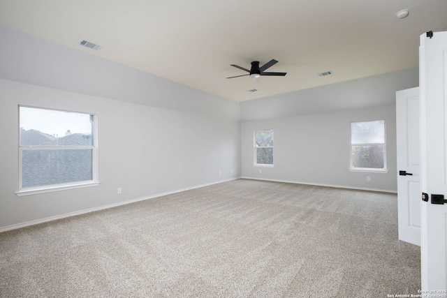 empty room featuring ceiling fan, light colored carpet, and plenty of natural light