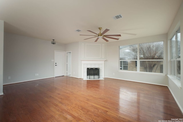 unfurnished living room featuring a tile fireplace, hardwood / wood-style flooring, and ceiling fan