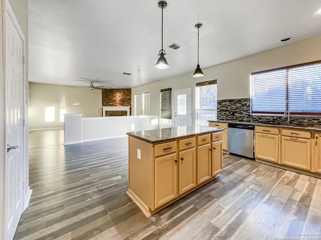 kitchen with decorative backsplash, decorative light fixtures, dark stone countertops, dishwasher, and a center island