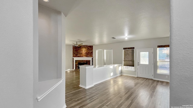 entryway featuring hardwood / wood-style floors, a brick fireplace, and ceiling fan