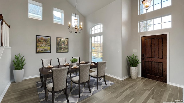 dining room with a towering ceiling, dark wood-type flooring, and a notable chandelier