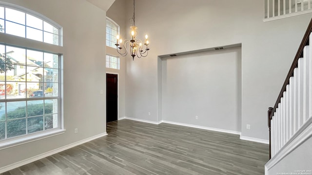 foyer entrance with a wealth of natural light, dark hardwood / wood-style flooring, a chandelier, and a high ceiling