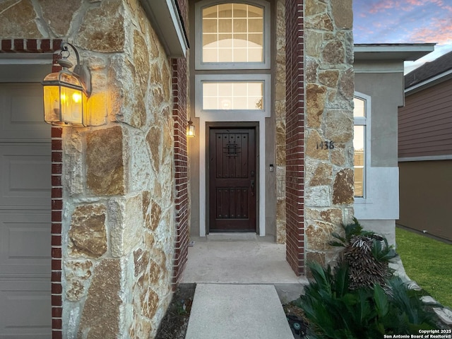 exterior entry at dusk featuring a garage