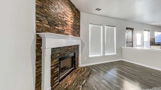 unfurnished living room featuring dark hardwood / wood-style floors and a stone fireplace