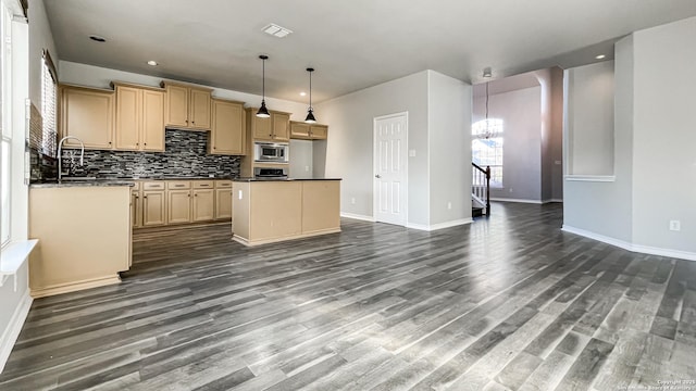 kitchen featuring stainless steel microwave, light brown cabinets, dark hardwood / wood-style floors, a chandelier, and pendant lighting