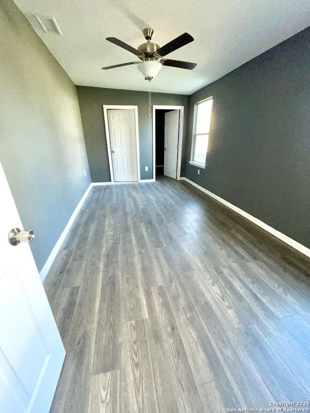 unfurnished bedroom featuring ceiling fan, dark wood-type flooring, and a textured ceiling