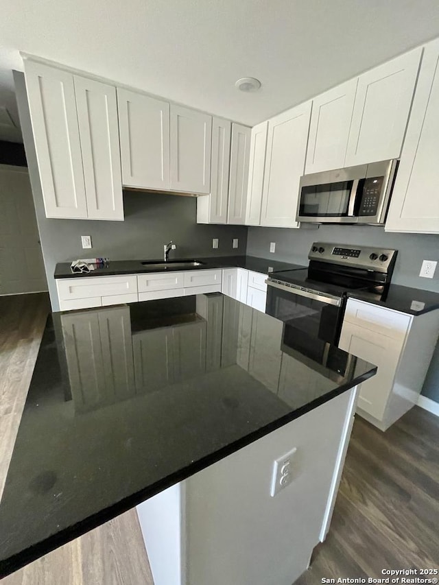 kitchen featuring dark hardwood / wood-style flooring, sink, white cabinetry, and stainless steel appliances