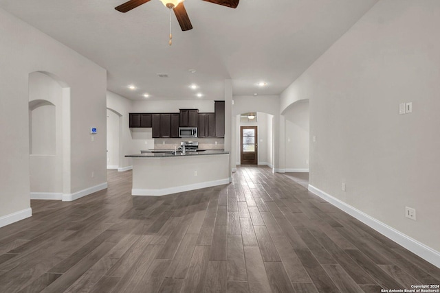 kitchen with ceiling fan, sink, dark wood-type flooring, and a kitchen island with sink