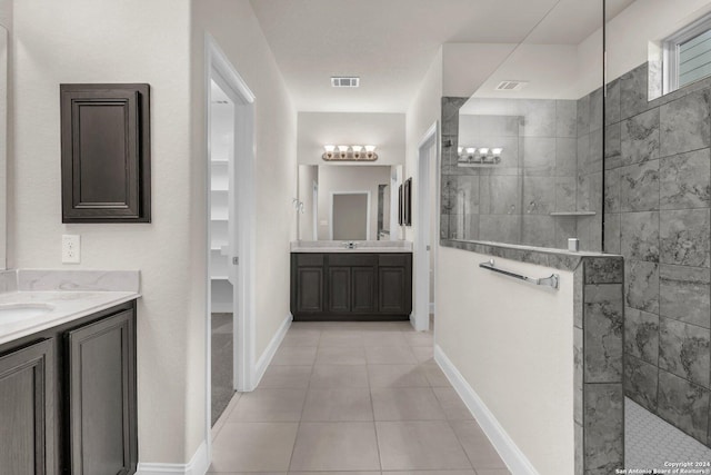 bathroom with tile patterned floors, vanity, and tiled shower