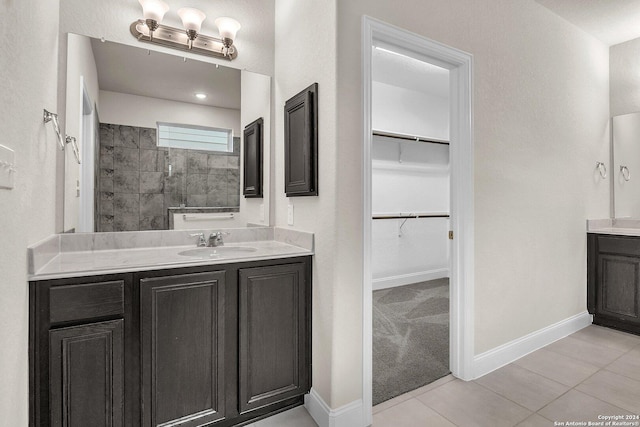 bathroom featuring tile patterned flooring, vanity, and a shower