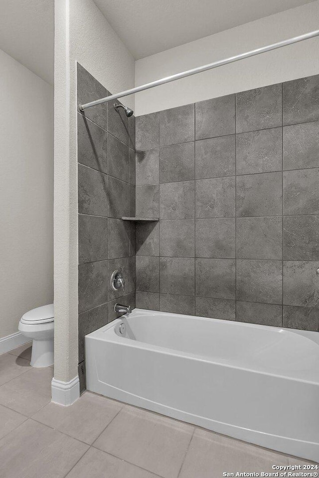 bathroom with toilet, tile patterned floors, and tiled shower / bath