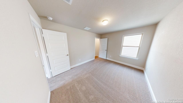 unfurnished bedroom featuring light colored carpet and a textured ceiling