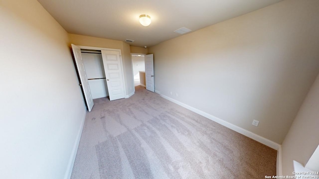 unfurnished bedroom featuring light colored carpet and a closet