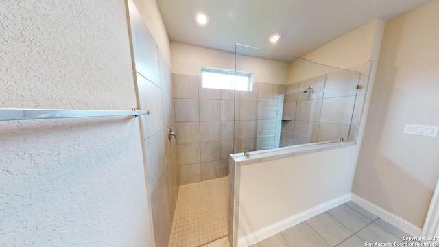 bathroom with tiled shower and tile patterned flooring