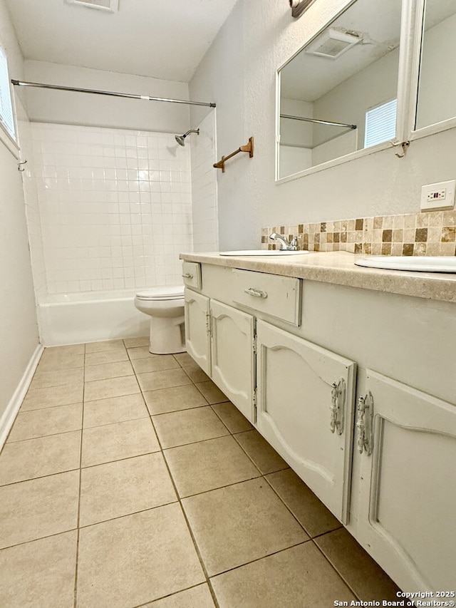 full bathroom featuring tiled shower / bath combo, tile patterned floors, toilet, decorative backsplash, and vanity