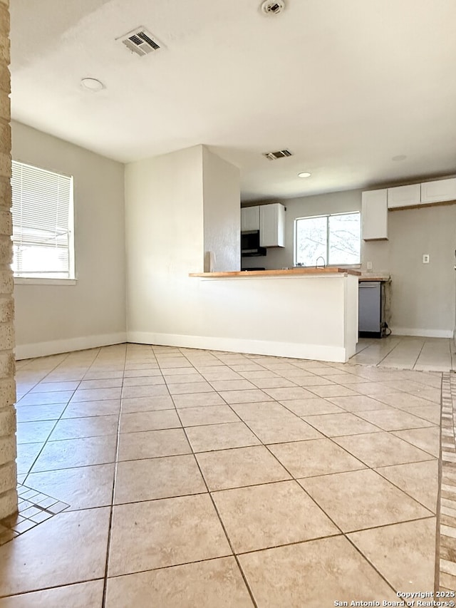 kitchen with white cabinets, kitchen peninsula, stainless steel appliances, and light tile patterned floors