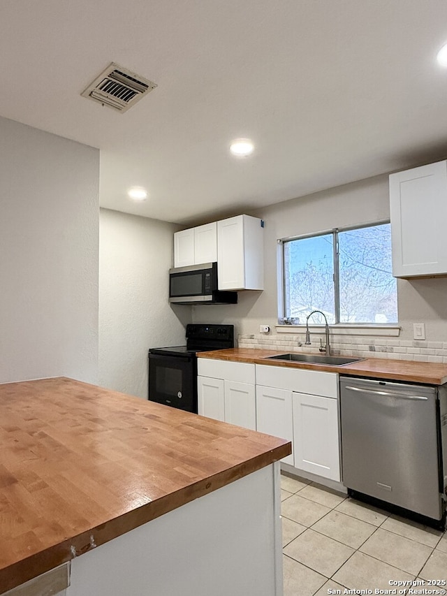 kitchen featuring wood counters, appliances with stainless steel finishes, sink, light tile patterned floors, and white cabinets