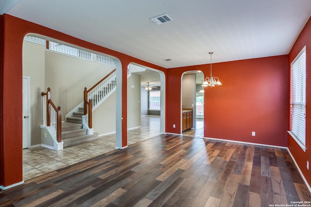 interior space featuring ceiling fan with notable chandelier and dark hardwood / wood-style floors